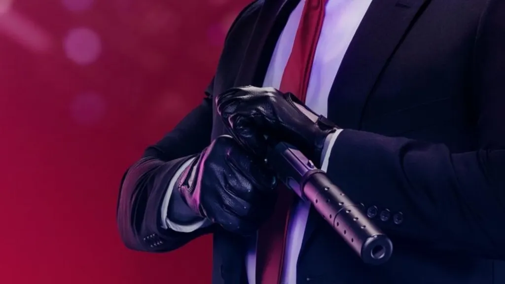 Zbliżenie na pistolet z tłumikiem na tle postaci w skórzanych rękawiczkach, czarnym garniturze, białej koszuli i z czerwonym krawatem.