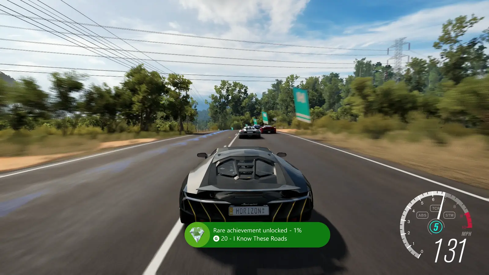 Kadr z gry Forza Horizon 3, auto wyścigowe sunące z dużą prędkością po drodze, na dole ekranu pasek osiągnięcia.