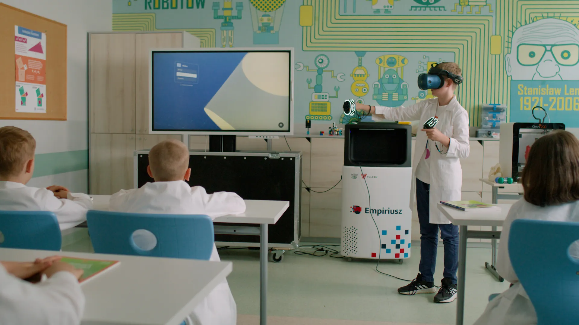 Wirtualne Laboratorium Empiriusz w praktyce: uczeń z goglami VR na głowie i kontrolerami w rękach stoi na wprost klasy. Z jakiegoś powodu wszyscy uczniowie ubrani są w fartuchy laboratoryjne.