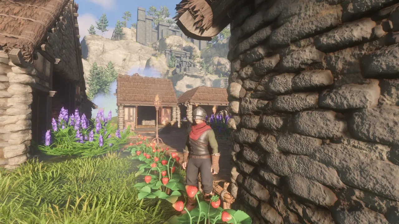 Grafika prezentuje postać w grze Enshrouded, która zwrócona jest w naszą stronę. W tle widać budynki, a na pierwszym planie sadzonkę truskawek.