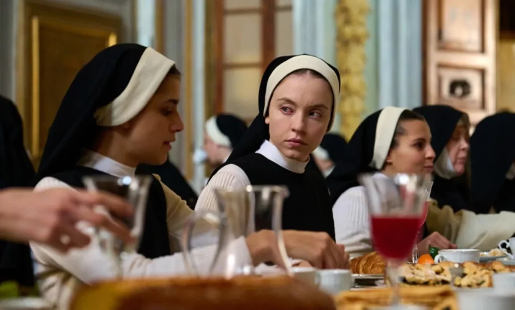 Horror Niepokalana - kadr z filmu. Główna bohaterka siedzi przy stole w jadalni wraz z innymi zakonnicami.
