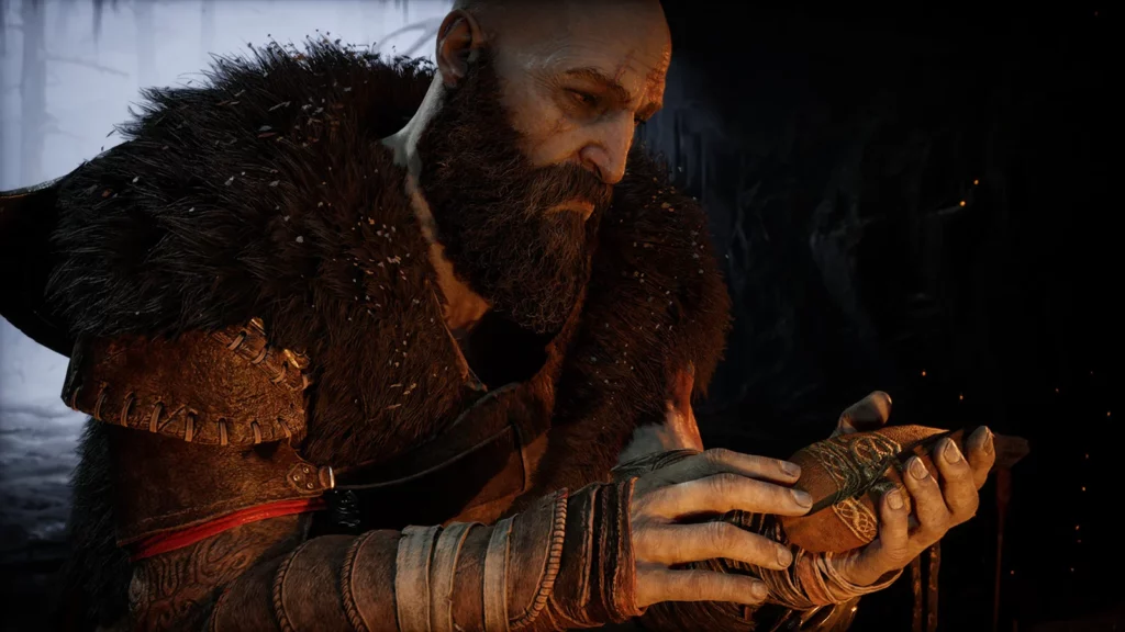 Kratos z poważnym wyrazem twarzy trzyma w dłoniach zdobiony amulet, pogrążony w głębokiej refleksji.