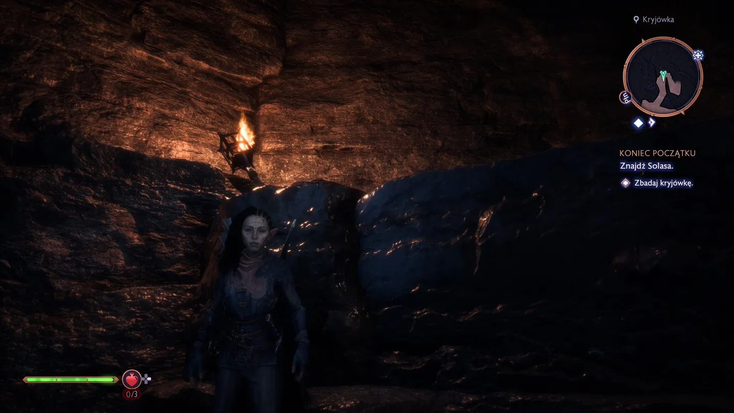 Mroczna jaskinia z płonącą pochodnią. Na pierwszym planie widoczna postać w ciemnym stroju, stojąca w półmroku. W prawym górnym rogu interfejs gry z napisem 'Znajdź Solasa' i zadaniem 'Zbadaj kryjówkę'.