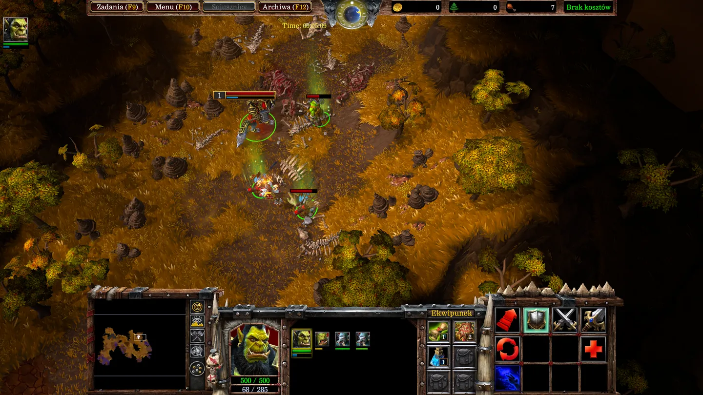 Zbliżenie na bohaterów walczących na polu bitwy w grze WarCraft III: Reforged. Widoczni są orkowie i inne fantastyczne stworzenia walczące ze sobą w gęstej roślinności. W dolnej części ekranu znajduje się rozbudowane menu i interfejs użytkownika.