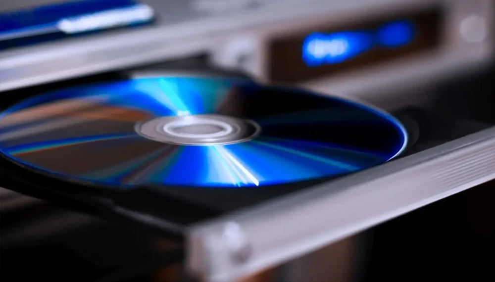 Płyta Blu-ray w napędzie, ukazująca charakterystyczną niebieską powierzchnię nośnika. Zbliżenie na błyszczącą powierzchnię z odbiciami światła.