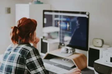 Kobieta przy komputerze sprawdza nowy monitor poleasingowy.