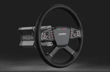 Kierownica Moza TSW Wheel z zamontowaną bazą, sfotografowana na ciemnym tle. Na środku kierownicy widoczne jest logo „MOZA RACING”, wokół którego rozmieszczone są podświetlane przyciski funkcyjne i pokrętła. U góry panel z kolorowymi diodami LED sygnalizującymi obroty silnika. Całość utrzymana w nowoczesnym, czarno-szarym designie.