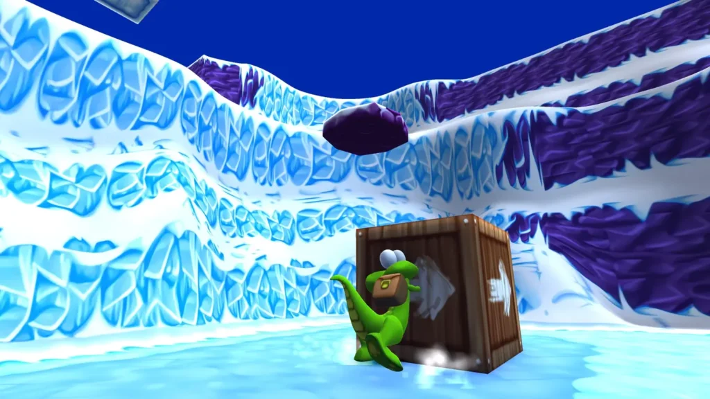 Zrzut ekrany z gry Croc: Legend of the Gobbon. Croc przesuwa pudełko z narysowanymi na nim strzałkami. Lodowe góry w tle.