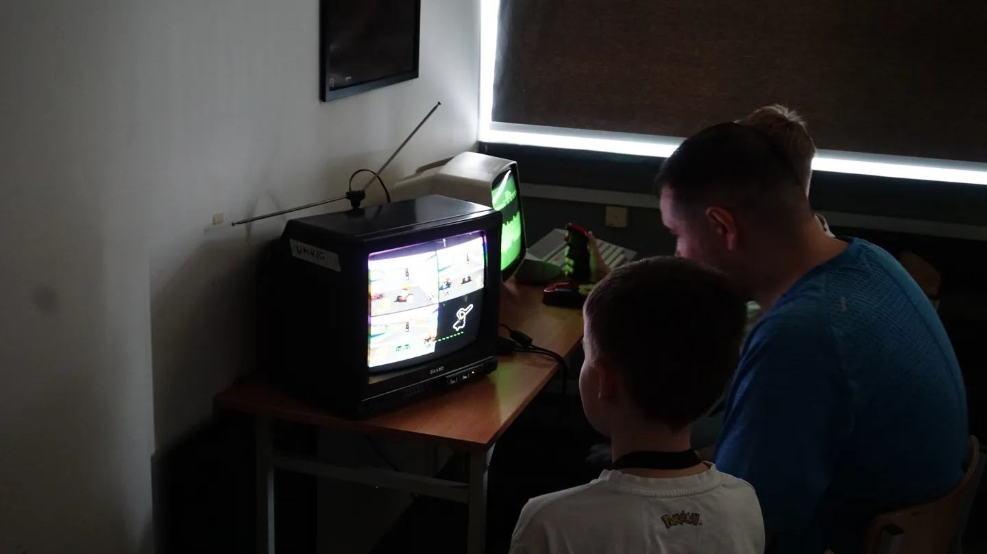 Uczestnicy Pixel Heaven 2025 grają razem w klasyczną grę wyścigową na starym telewizorze CRT, ciesząc się klimatem dawnych lat