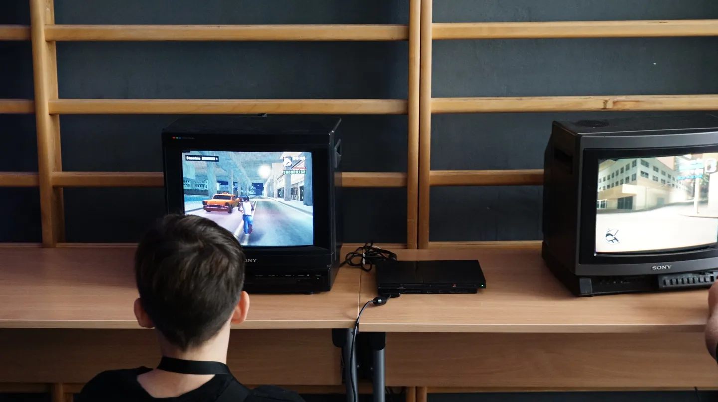 Strefa retro gamingu na Pixel Heaven 2025. Uczestnicy grają na klasycznych konsolach PlayStation 2 podłączonych do starych telewizor&oacute;w CRT, przenosząc się do klimatu dawnych lat.