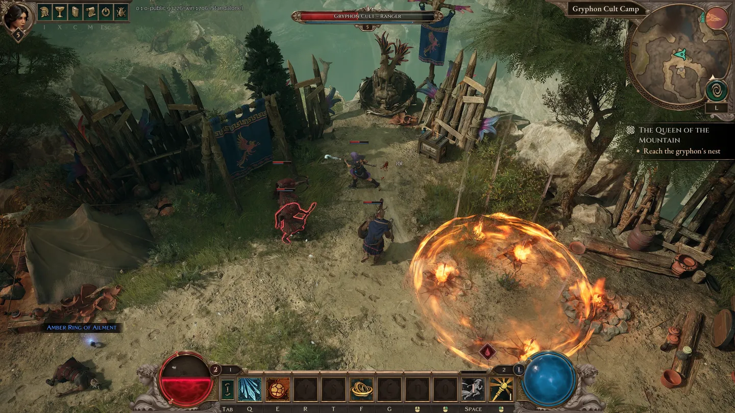 Obraz przedstawia fragment rozgrywki w grze Titan Quest II, ukazanej w rzucie izometrycznym. Na niewielkim obozowisku przy drewnianych palisadach i niebieskich sztandarach z gryfem toczy się walka &ndash; postać gracza mierzy się z dwoma przeciwnikami oznaczonymi na czerwono. Na ziemi widać płonącą pułapkę lub efekt umiejętności, tworzący pomarańczową, rozżarzoną aurę. Po lewej widoczny jest namiot, skrzynie i rozrzucone przedmioty, po prawej rośnie gęste drzewo, a w tle rozpościera się skalista skarpa nad rzeką. U dołu ekranu znajduje się interfejs z paskiem zdrowia i many, ikonami umiejętności oraz minimapą i celami zadania (&bdquo;Reach the gryphon&rsquo;s nest&rdquo;).