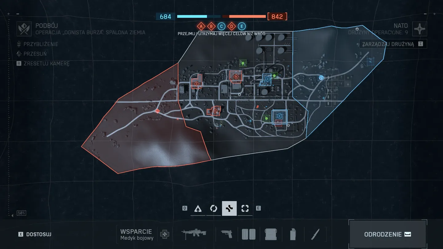 Mapa rozgrywki &bdquo;Podb&oacute;j&rdquo; w trybie operacji &bdquo;Ognista Burza: Spalona Ziemia&rdquo;, pokazująca rozkład punkt&oacute;w kontrolnych, pozycje drużyn oraz granice terytori&oacute;w obu stron; na dole ekranu widoczne są ikony klas oraz ekwipunku w trybie wsparcia.