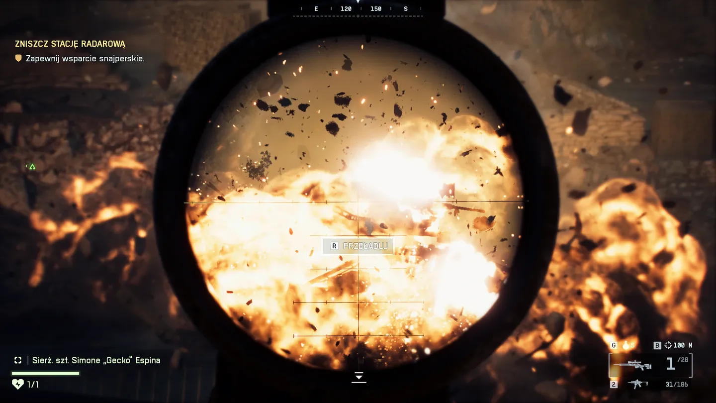Zbliżenie przez lunetę snajperską na potężną eksplozję &ndash; ekran wypełniają płomienie, unoszące się odłamki i fala uderzeniowa, a w HUD wyświetla się przeładowanie amunicji i cel związany z misją zniszczenia stacji radarowej.
