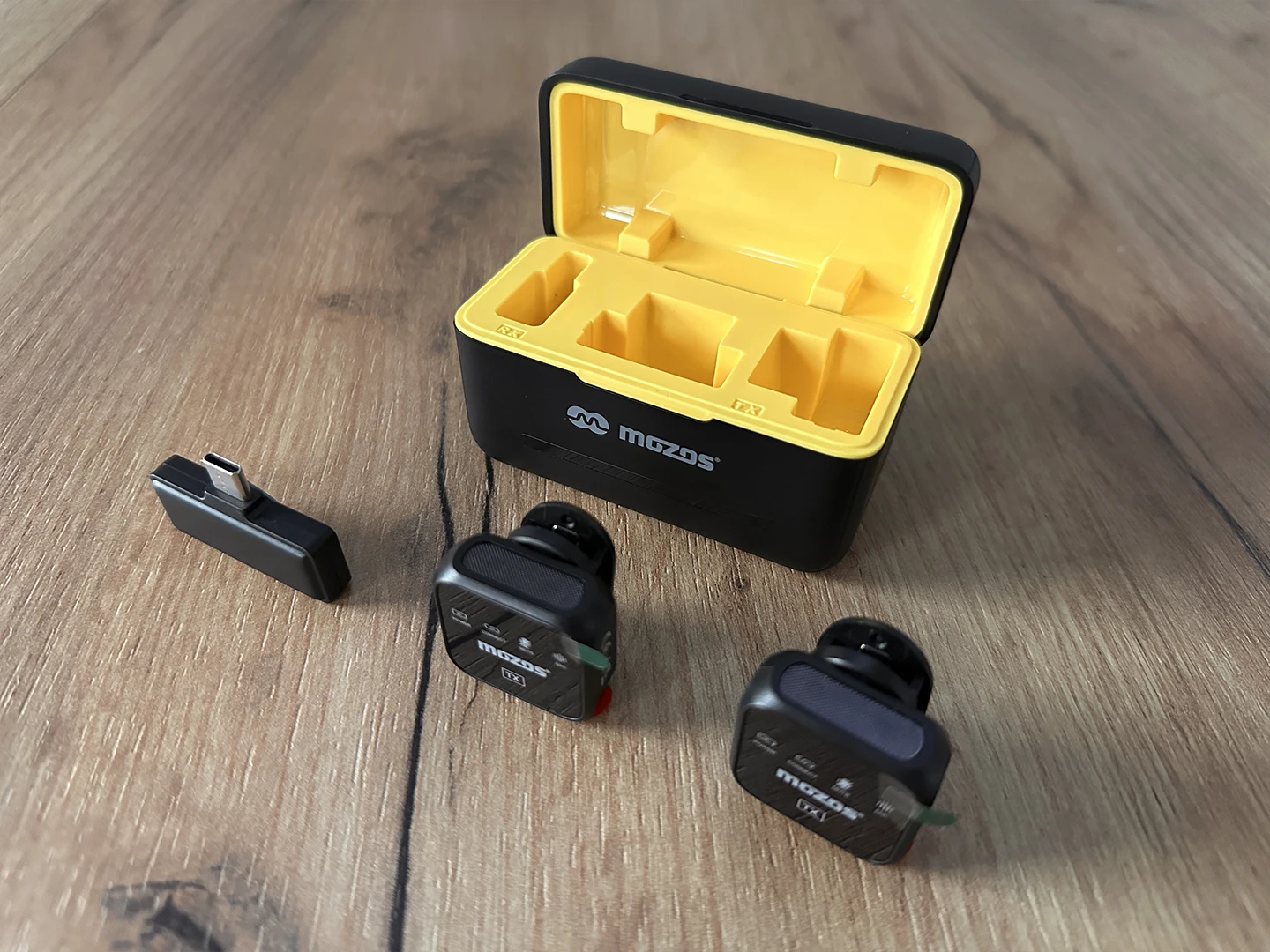 Dwa mikrofony, nadajnik oraz etui ładujące.