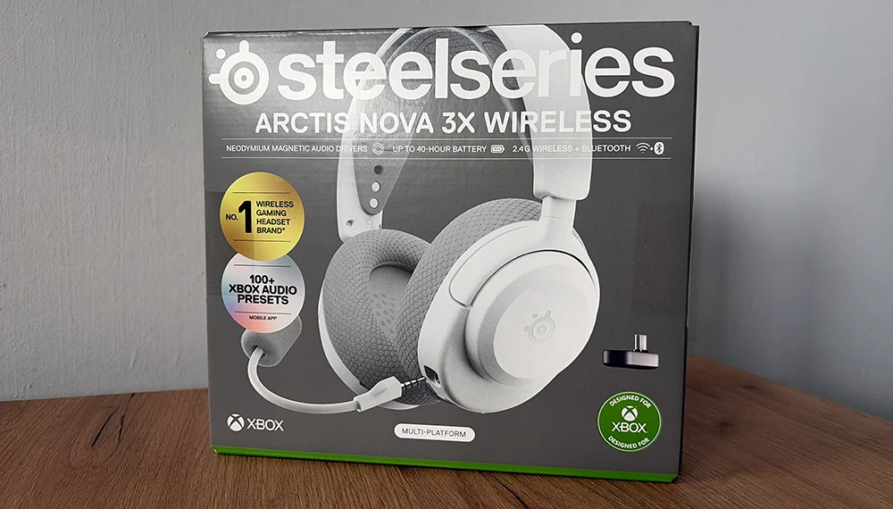 Pudełko SteelSeries Arctis Nova 3X Wireless na drewnianym stole.