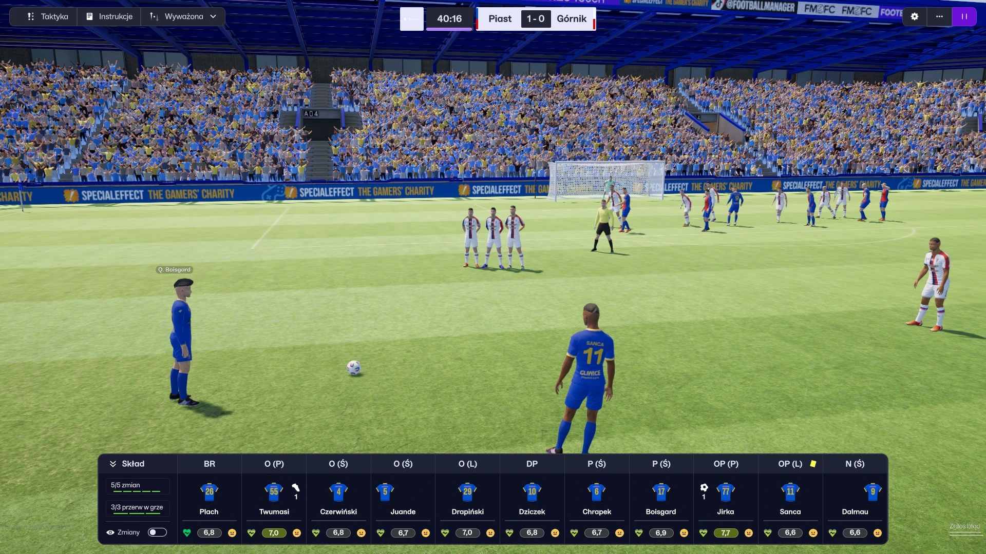Widok z gry FM26 pokazujący widok meczowy. W tym momencie jedna z drużyn podczas meczu Piast - Górnik przygotowuje się do wykonania rzutu wolnego.