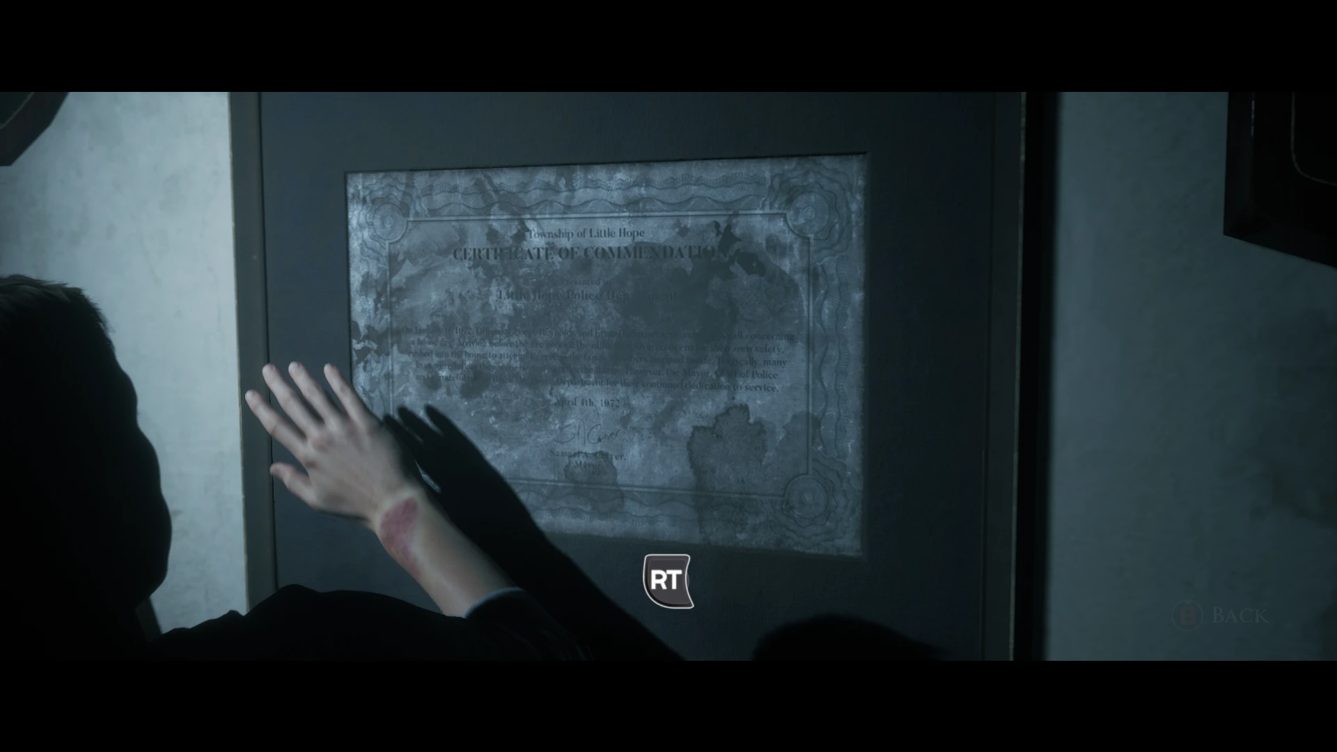 Little Hope - ktoś macha ręką do tablicy naściennej