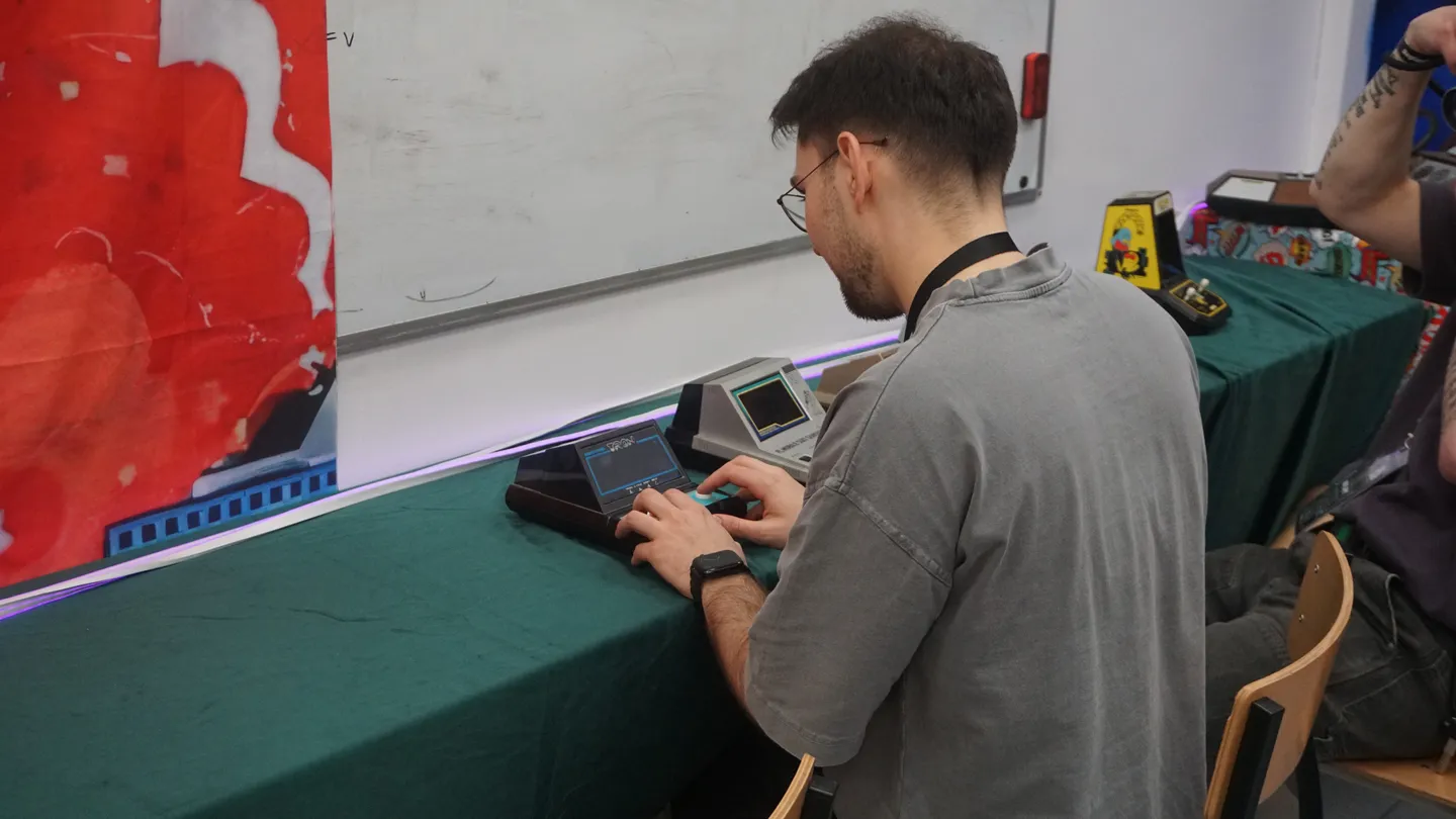 Osoba grająca na małym retro sprzęcie typu tabletop przy stoliku na ReplayFest
