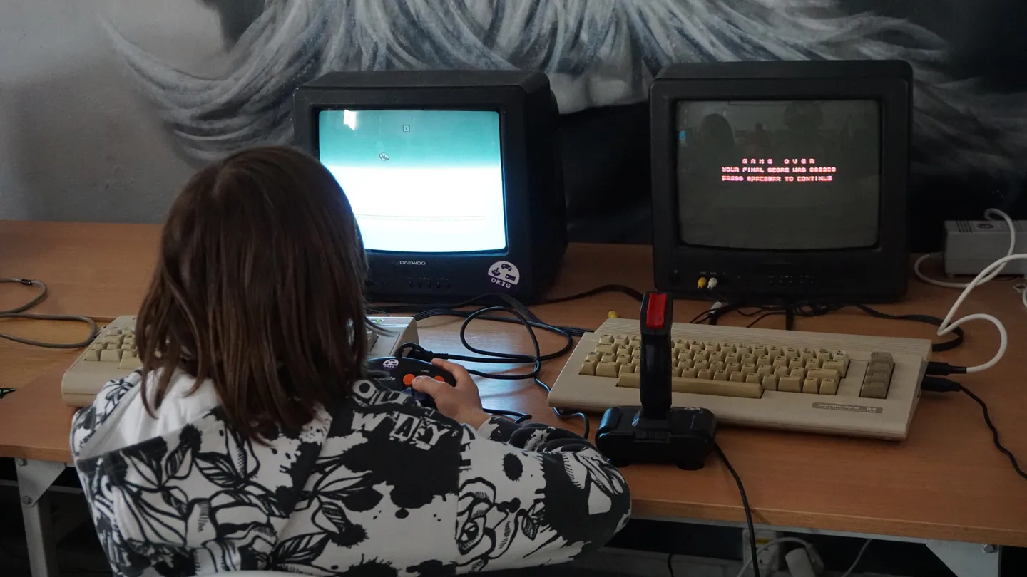 Uczestnik ReplayFest 2026 grający na retro komputerach przy stanowisku z monitorami CRT