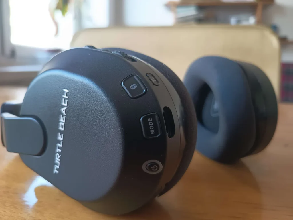Zbliżenie na lewą muszlę słuchawek Turtle Beach Stealth 600 Gen 3 z widocznymi przyciskami funkcyjnymi i logo na obudowie.