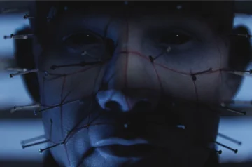 Kadr z gry Hellraiser: Revival, zbliżenie twarzy Pinheada, postaci z gry. Blada twarz istoty ponabijana jest igłami