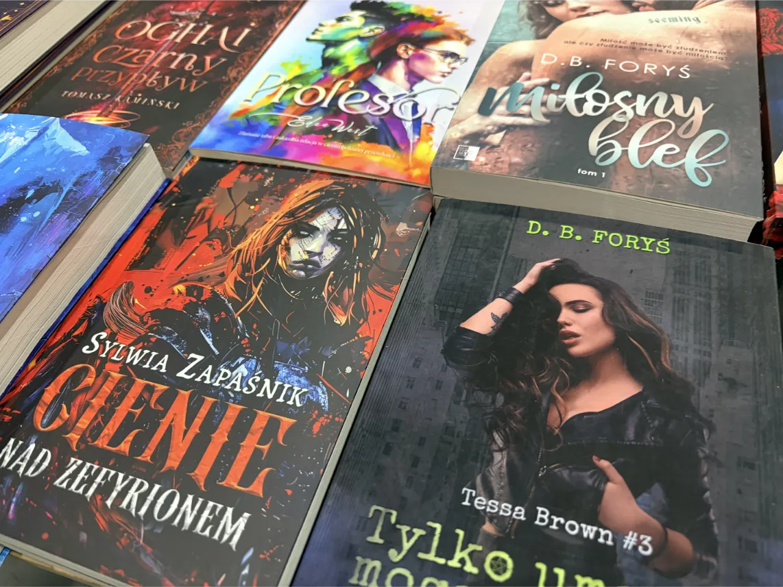 Pyrkon 2026: Bliskie ujęcie prezentuje stosy polskich książek fantastycznych, sci-fi oraz obyczajowych wyłożonych na konwentowym stole.