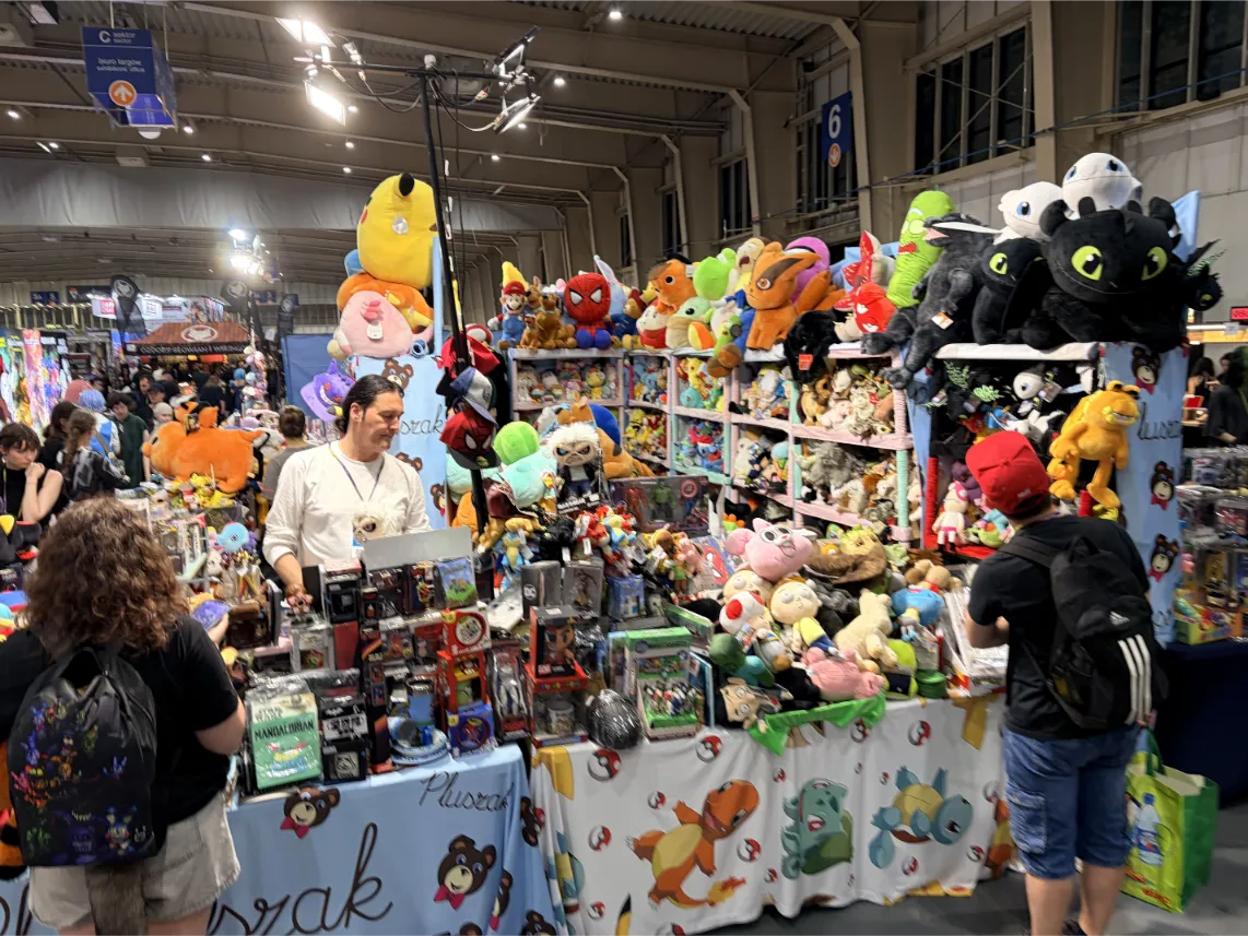 Pyrkon 2026: Zdjęcie przedstawia kolorowe stoisko handlowe po brzegi wypełnione pluszowymi maskotkami z popularnych gier, bajek i animacji, m.in. Pikachu, Spider-Mana, Scooby-Doo czy Szczerbatka.
