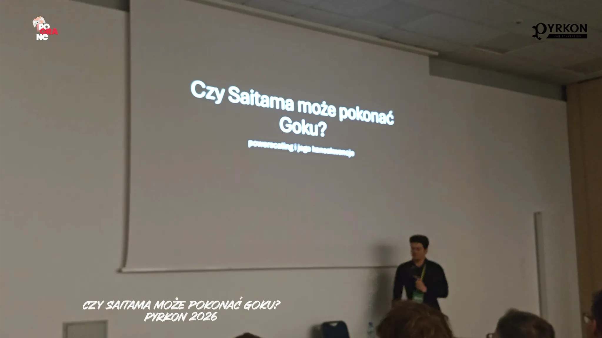 zdjęcie prezentuje kadr z panelu dyskusyjnego dotyczącego anime i mangi. Na dole ekranu widnieje nałożony tekst: „CZY SAITAMA MOŻE POKONAĆ GOKU? PYRKON 2026”.