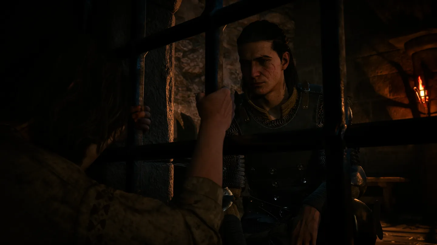 Bohater gry The Blood of Dawnwalker rozmawia z postacią za kratami w ciemnym, podziemnym pomieszczeniu.