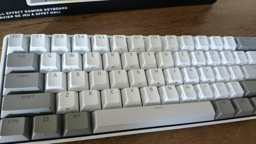 Klawiatura Corsair 60% widziana z góry pod lekkim kątem na drewnianym blacie, prezentująca układ klawiszy bez podświetlenia.
