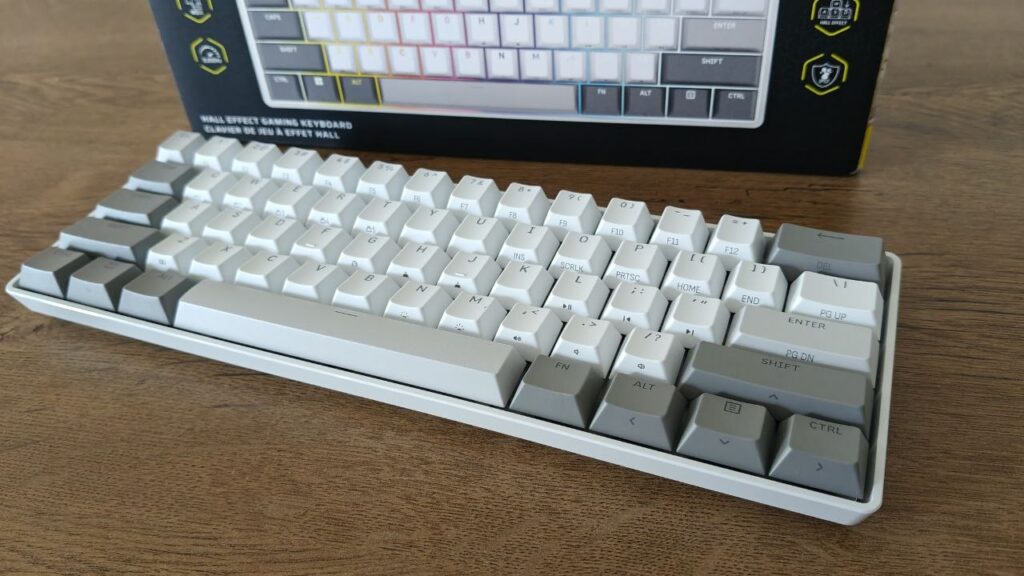 Otwarte żółto-czarne pudełko z klawiaturą Corsair Clipper Pro Mini 60 i dołączoną ulotką dotyczącą bezpieczeństwa.