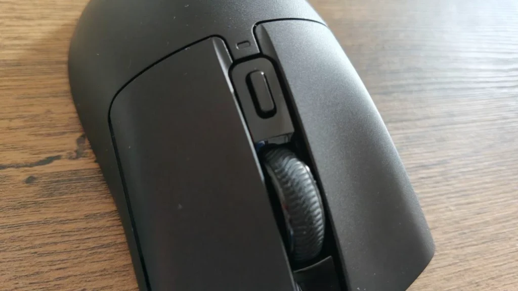 Czarna ergonomiczna mysz gamingowa Zircon 880 Pro na drewnianym biurku, widok z góry z bliska. Widoczne dwa główne przyciski, centralna rolka przewijania oraz dodatkowy przycisk nad rolką.