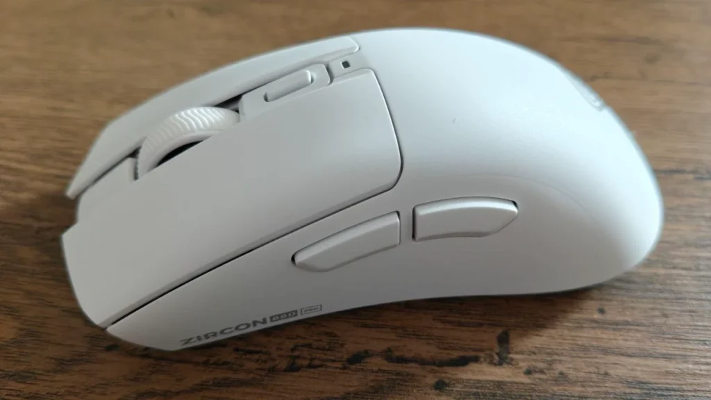 Biała ergonomiczna mysz gamingowa Zircon 880 Pro na drewnianym biurku, widok z boku. Widoczne dwa przyciski boczne, rolka przewijania, dodatkowy przycisk nad rolką oraz oznaczenie „ZIRCON 880 PRO” na obudowie.