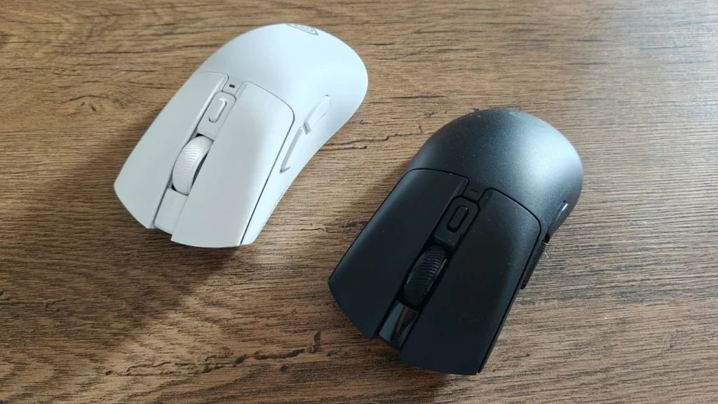 Biała i czarna myszy gamingowe Zircon 880 Pro ustawione obok siebie na drewnianym biurku, widok z góry pod kątem. Obie mają ergonomiczną obudowę, centralną rolkę przewijania i dodatkowe przyciski boczne.
