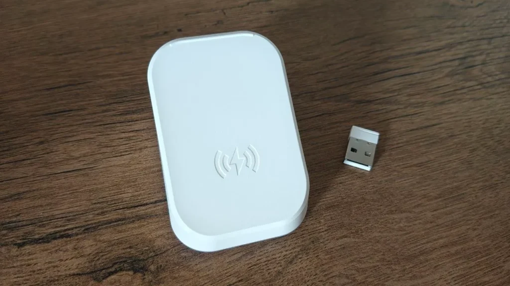 Górna powierzchnia magnetycznej stacji ładującej oraz leżący obok nano-odbiornik USB MCHOSE.