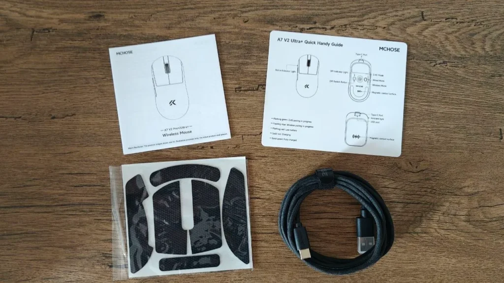 Zawartość zestawu MCHOSE: instrukcje obsługi, czarny kabel w oplocie USB-C oraz zestaw naklejek antypoślizgowych