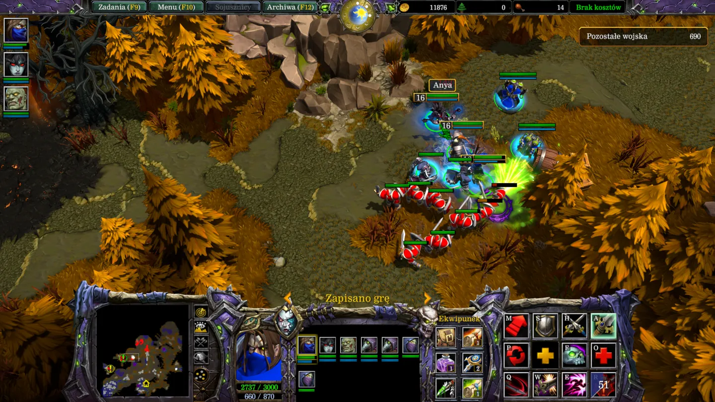 Zrzut ekranu z Warcraft III: Reforged – Forsaken Kingdom przedstawiający dużą bitwę w jesiennym lesie. Bohaterowie, w tym Anya, prowadzą oddział przeciwko grupie czerwono umundurowanych przeciwników, a na ekranie widnieje komunikat „Zapisano grę”.
