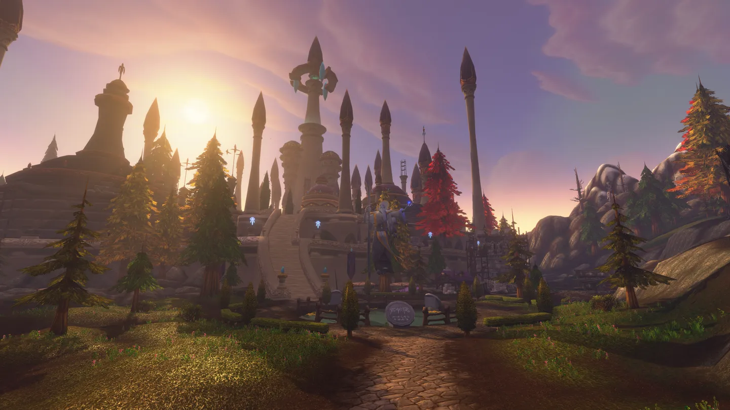 Widok górskiej krainy w World of Warcraft z monumentalną kamienną budowlą, posągami i alejką oświetloną zachodzącym słońcem.