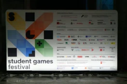 Na obrazie widoczny jest biały panel z logo i nazwą „student games festival”. Panel zawiera również logo i nazwy sponsorów i partnerów, w tym nazwy takich jak AMD, DGA, Intel, i innych.