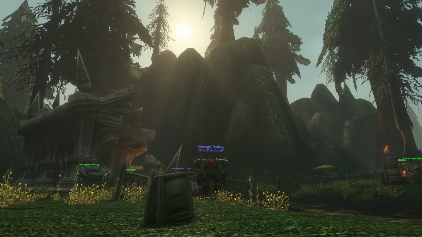 Klimatyczny zrzut ekranu z World of Warcraft przedstawiający orka maga „Koicagis Fistfury” stojącego w mrocznej, leśnej lokacji. W tle widać ogromne omszałe skały, wysokie drzewa iglaste oraz fragment kamiennej budowli, a słońce przebija się przez korony drzew.